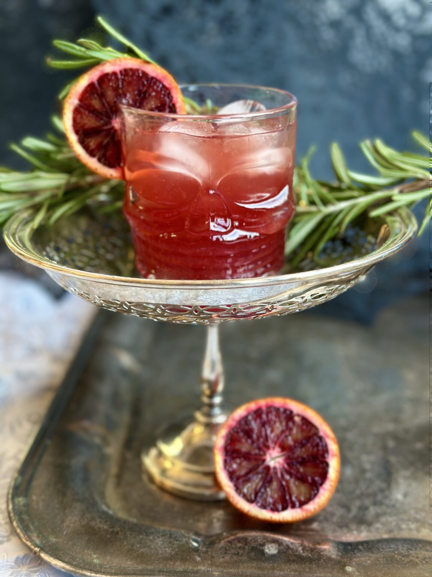 A blood orange and black currant aperol spritz served in a halloween themed glass on a silver tray