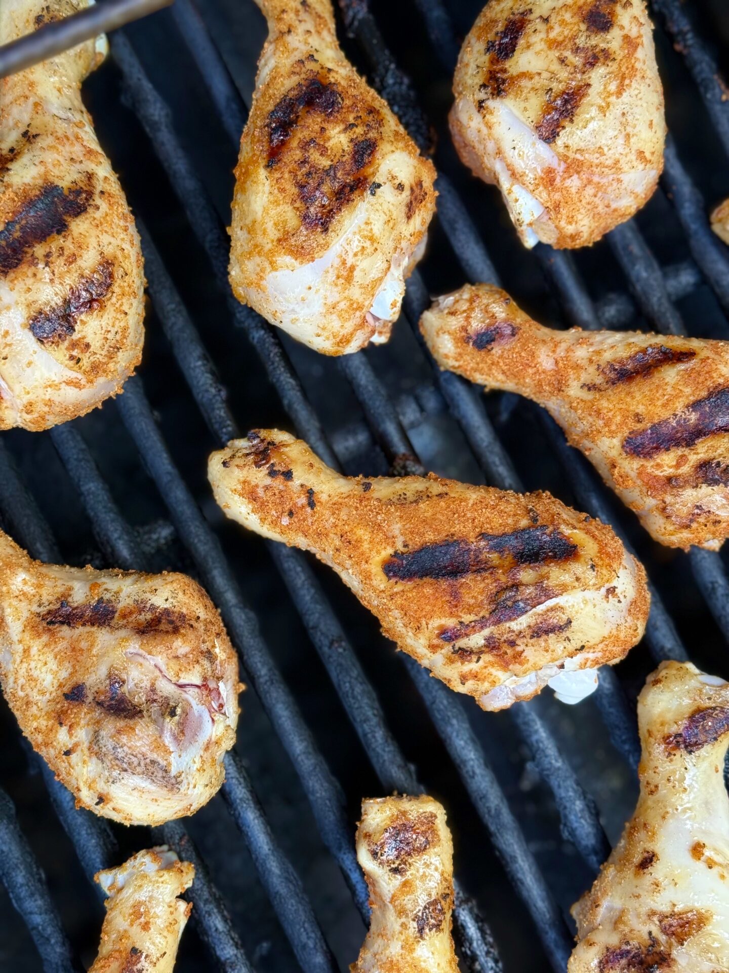 Chicken Legs with perfect grill marks are seen from above on a hot grill. 
