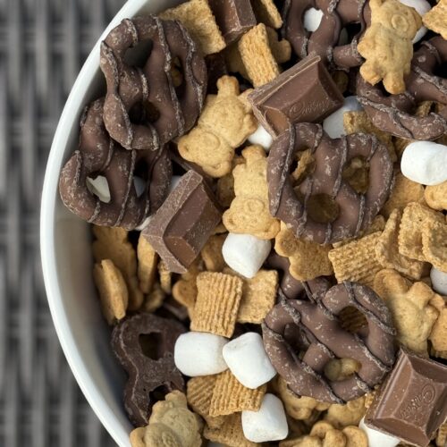 A bowl of S’Mores Snack Mix is seen from above sitting on a wicker table.