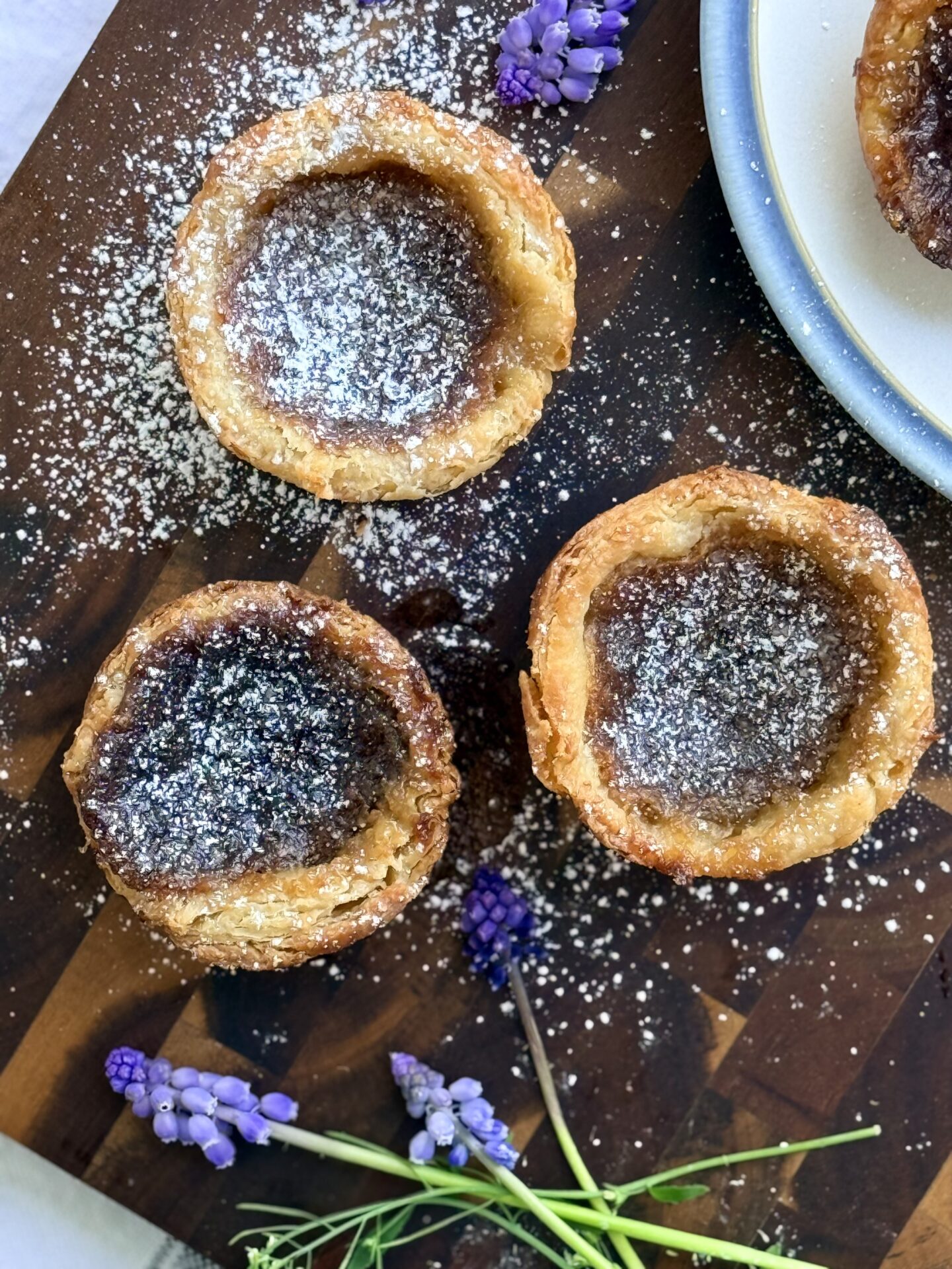 A trio of butter tarts with flaky, golden crusts and a rich caramel filling are seen from above