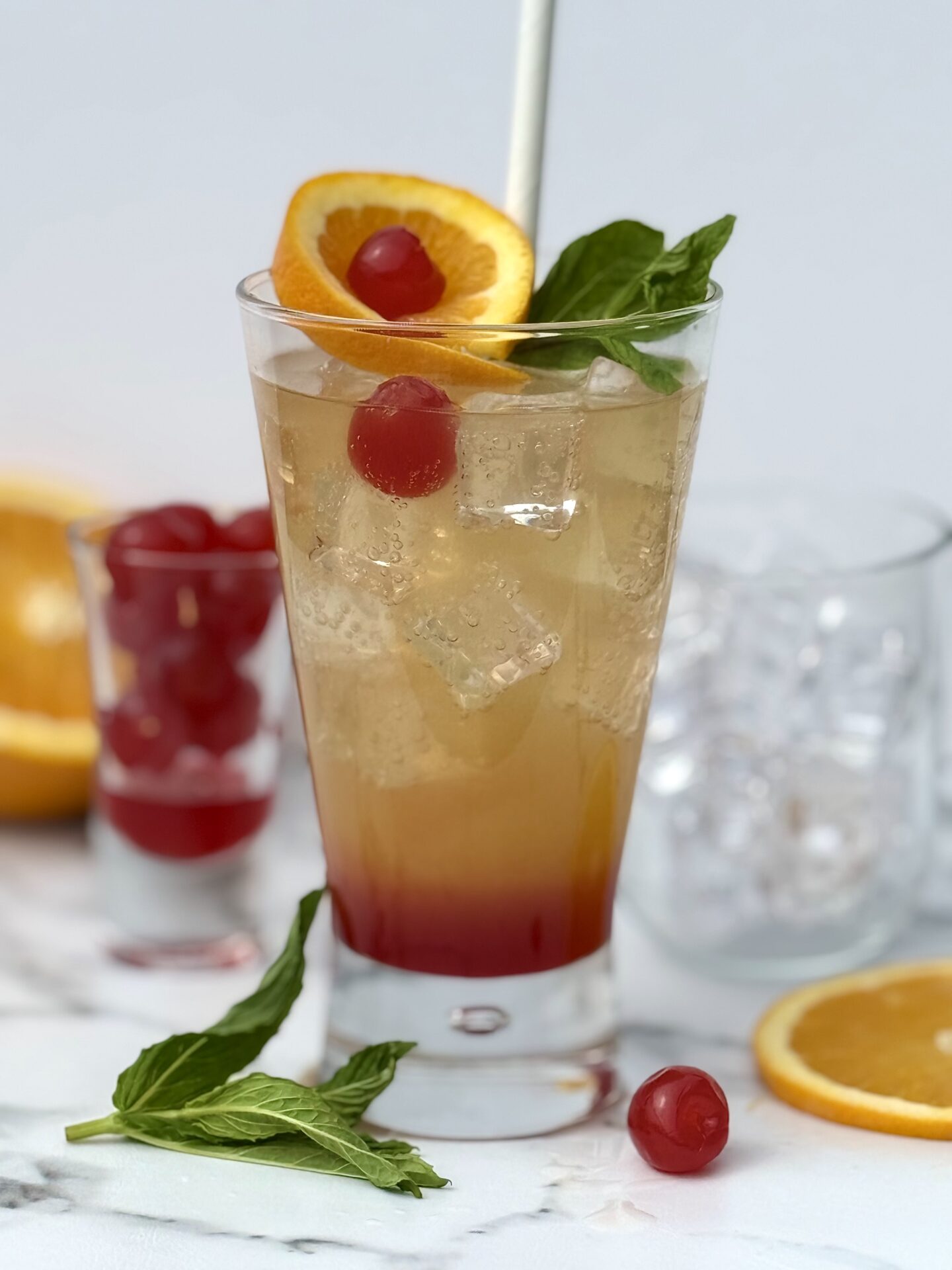 A tall glass of Shirley Temple mocktail is seen lavishly garnished with cherries.