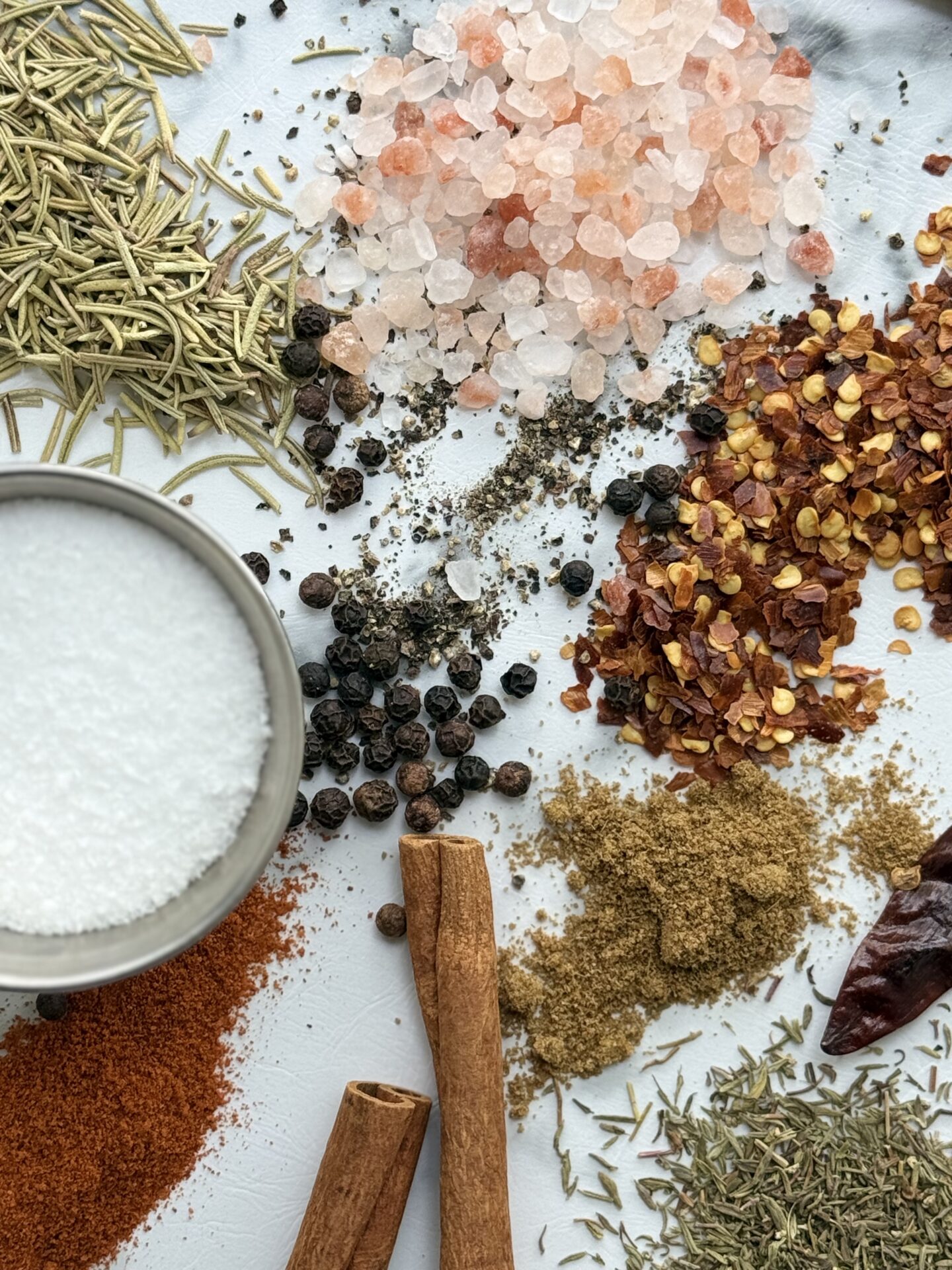 A selection of dried herbs and spices is spilled on a countertop
