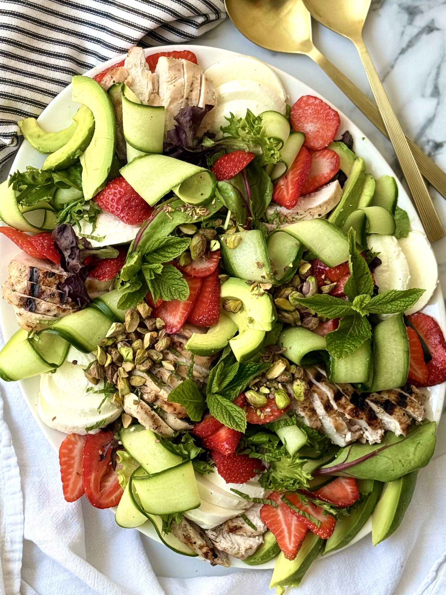 A large platter is seen from above, filled with a beautiful and vibrant summer salad.