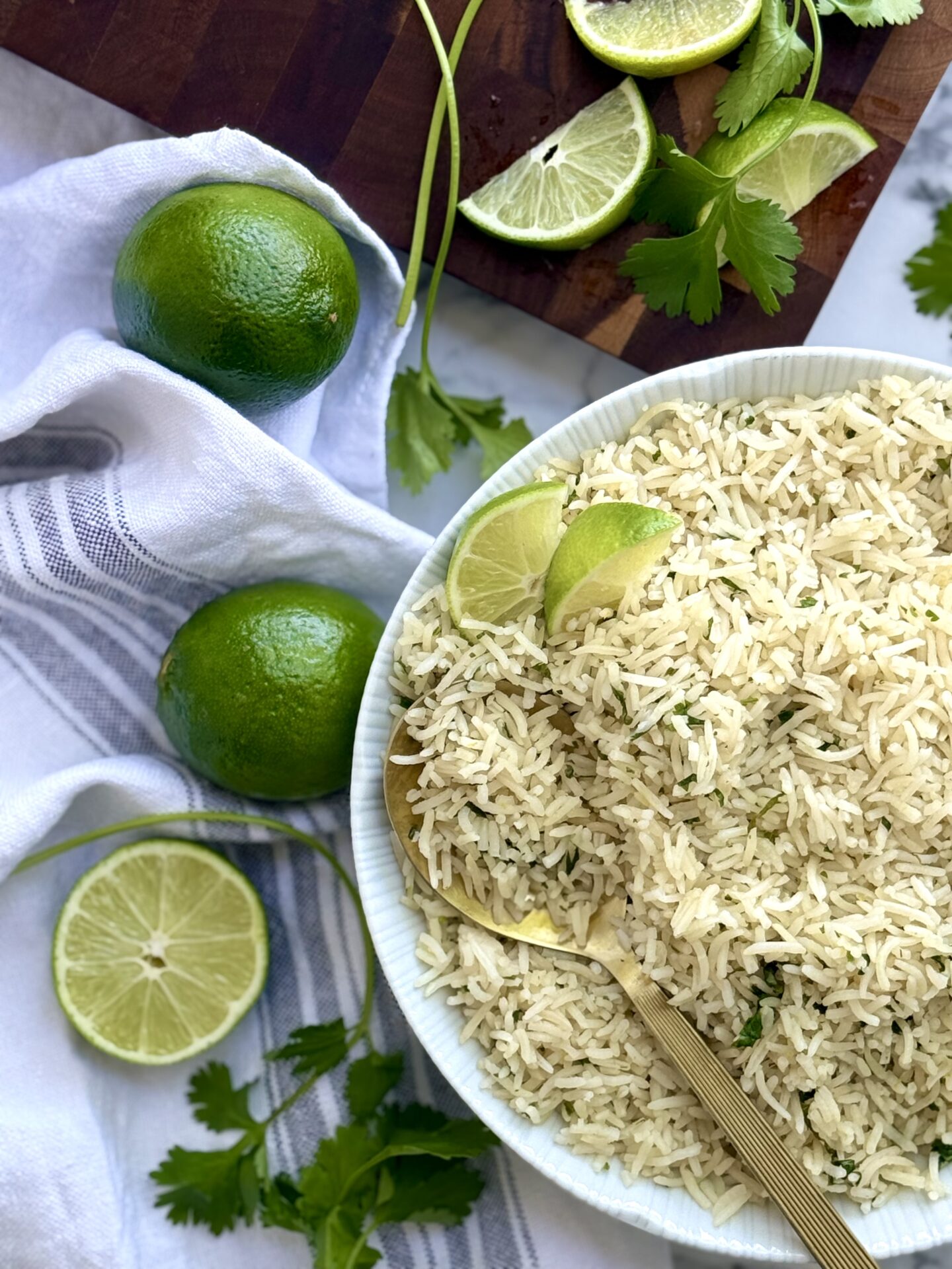 A bowl of cilantro lime rice is seen in the corner of the frame, surrounded by fresh lime & cilantro