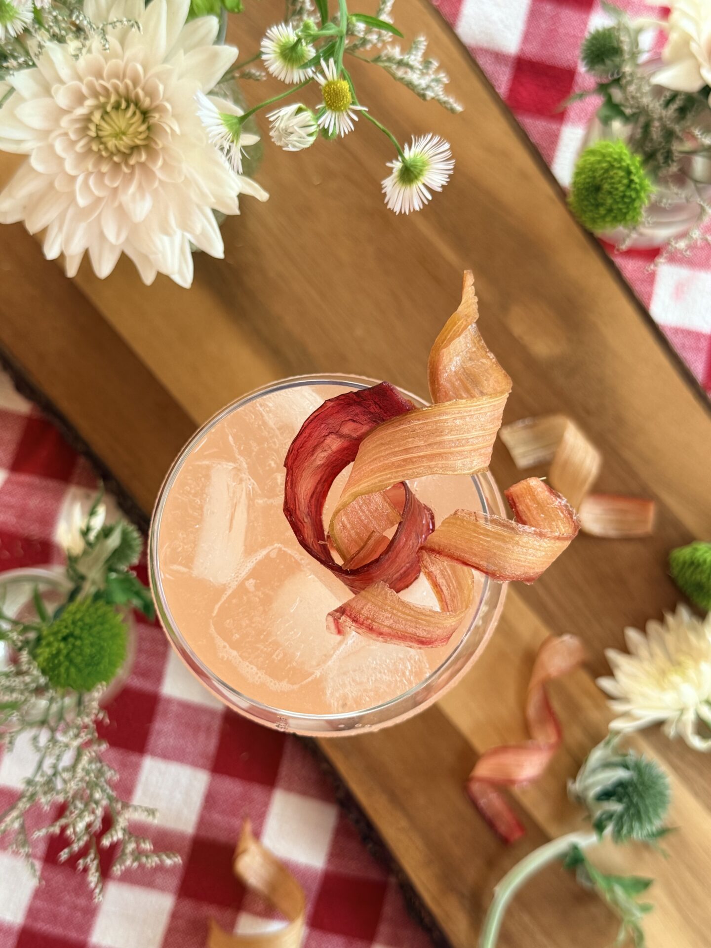 An icy pink drink is seen from above, lavishly garnished with candied rhubarb ribbons.