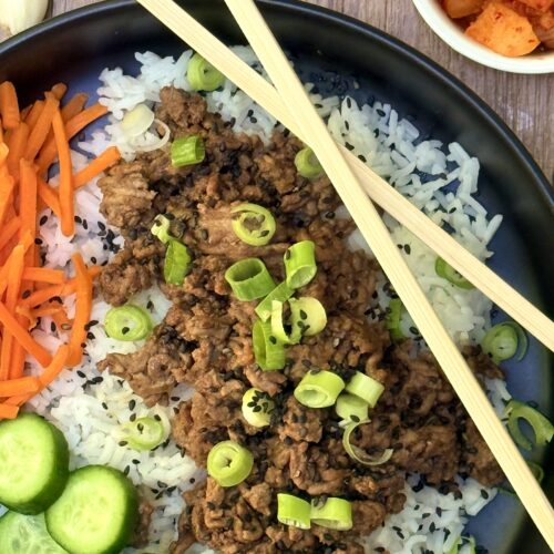 A Korean Ground Beef Bowl meal is seen close up, showing the beef in a rich sauce and the vibrant and crunchy vegetables all served over a bed of fluffy rice.