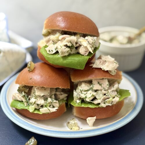 Three golden buns are seen overflowing with Greek Yogurt Dill Pickle Chicken salad.