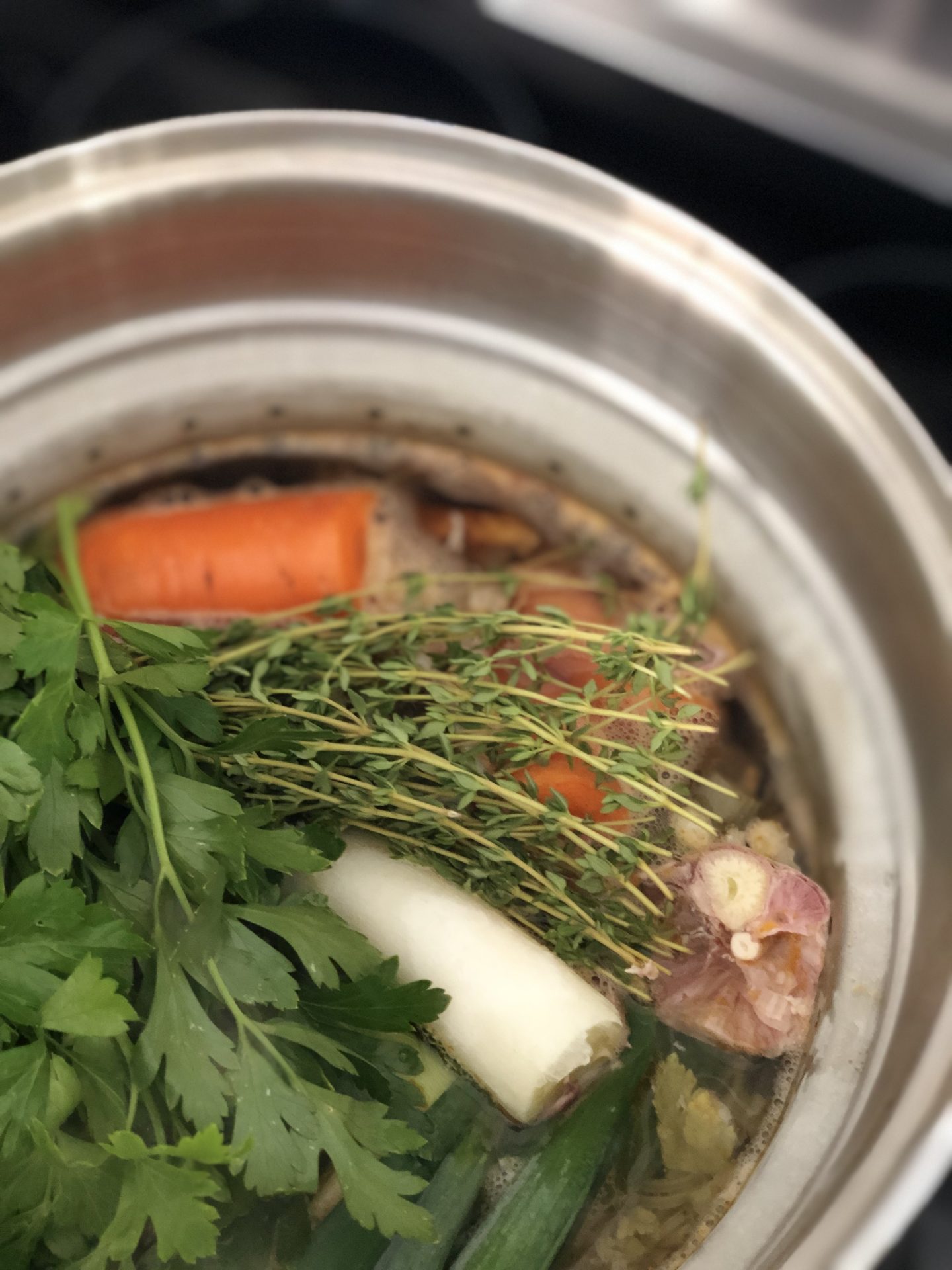 Fresh vegetables, herbs and chicken bones simmer away in a large stainless steel pot