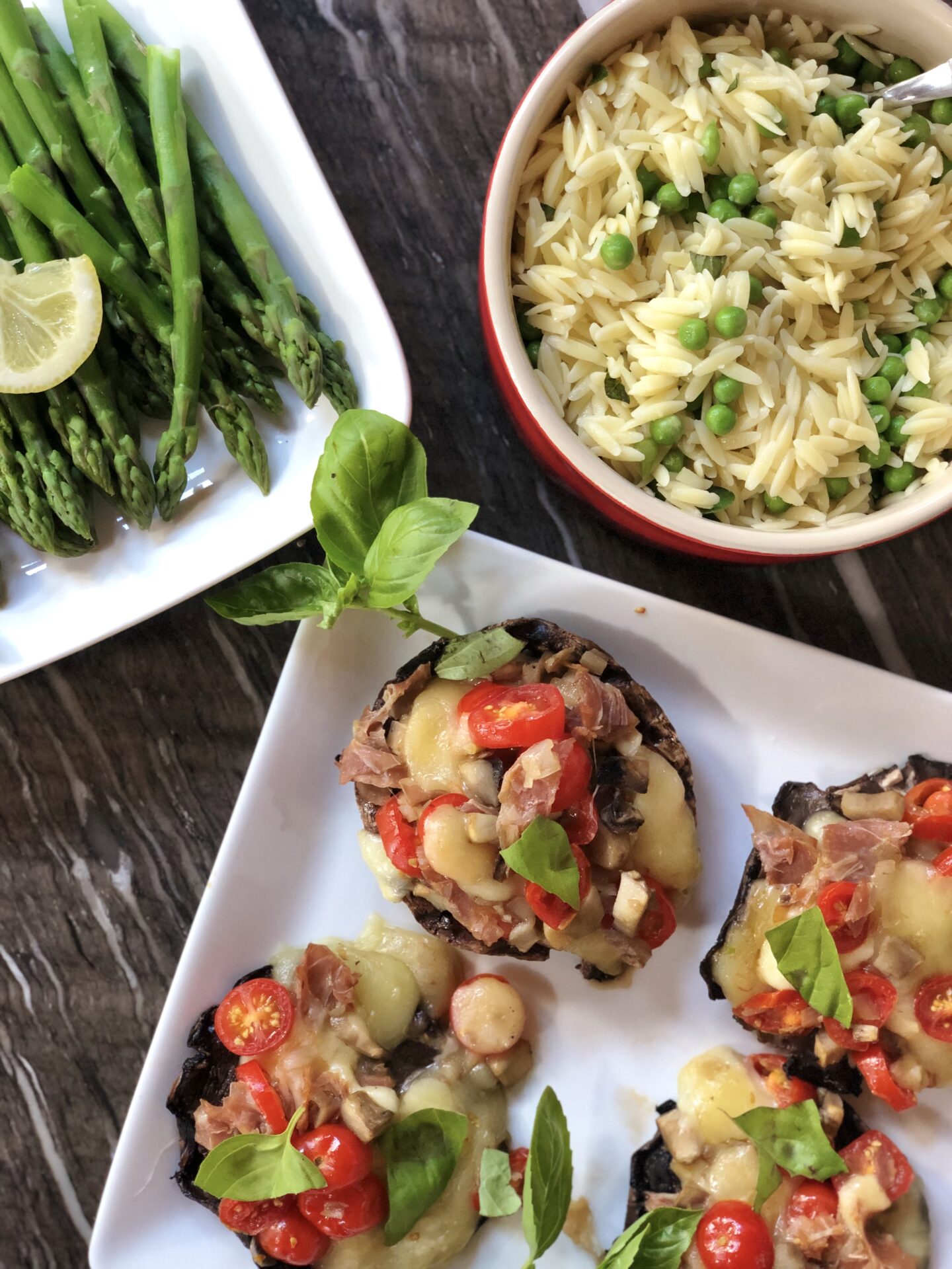 Bowls and platters of stuffed mushrooms, orzo pasta and asparagus