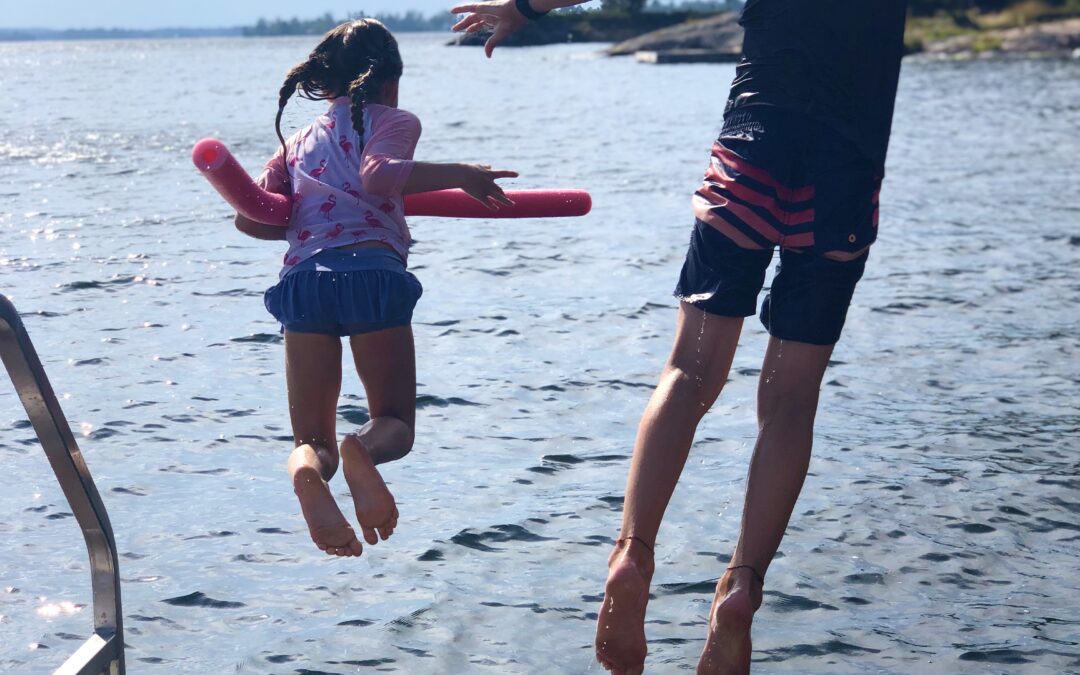 Kids jumping off a dock into a lake