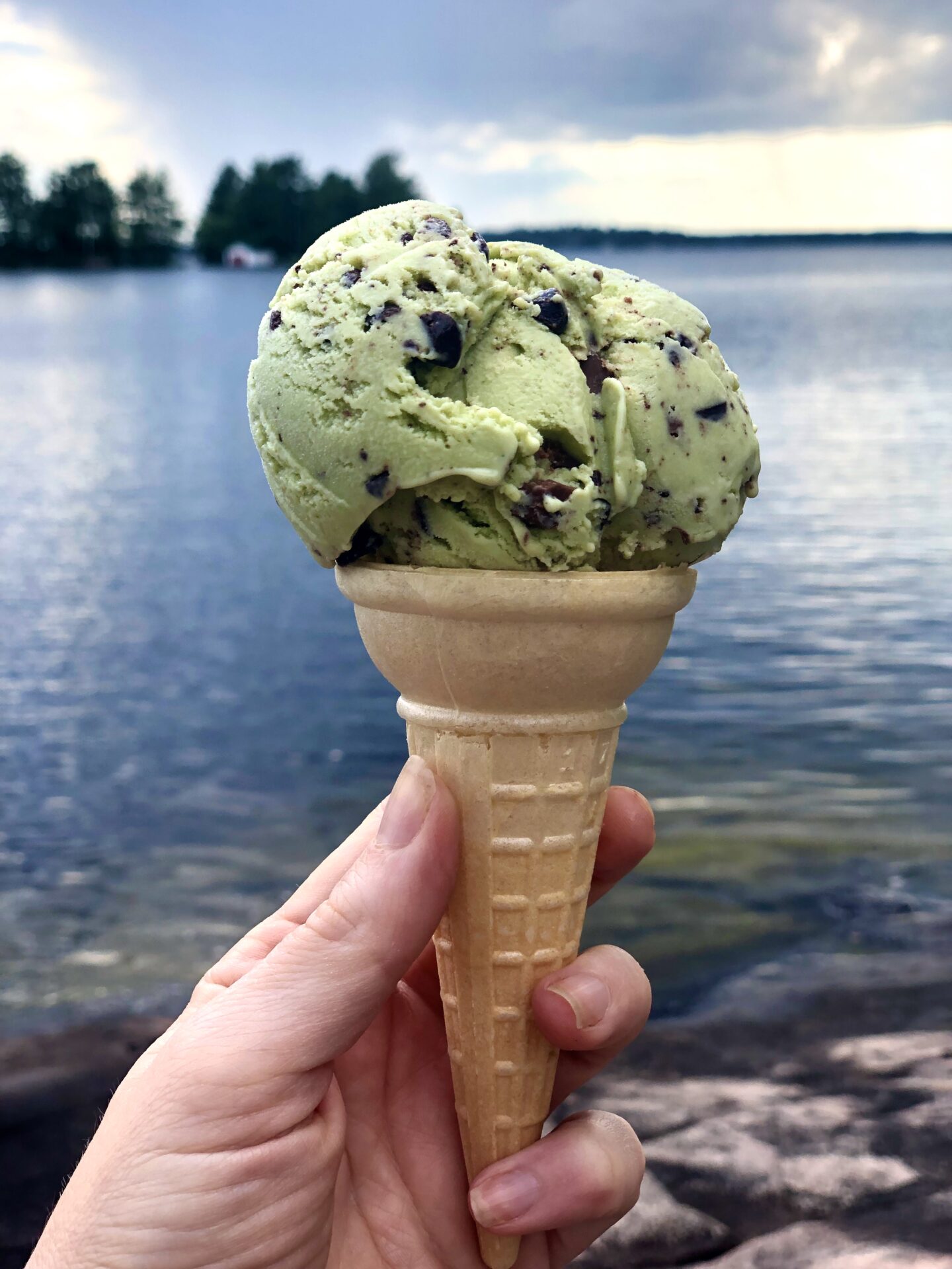 Homemade Mint Chocolate Chip Ice cream in a cone by the shore