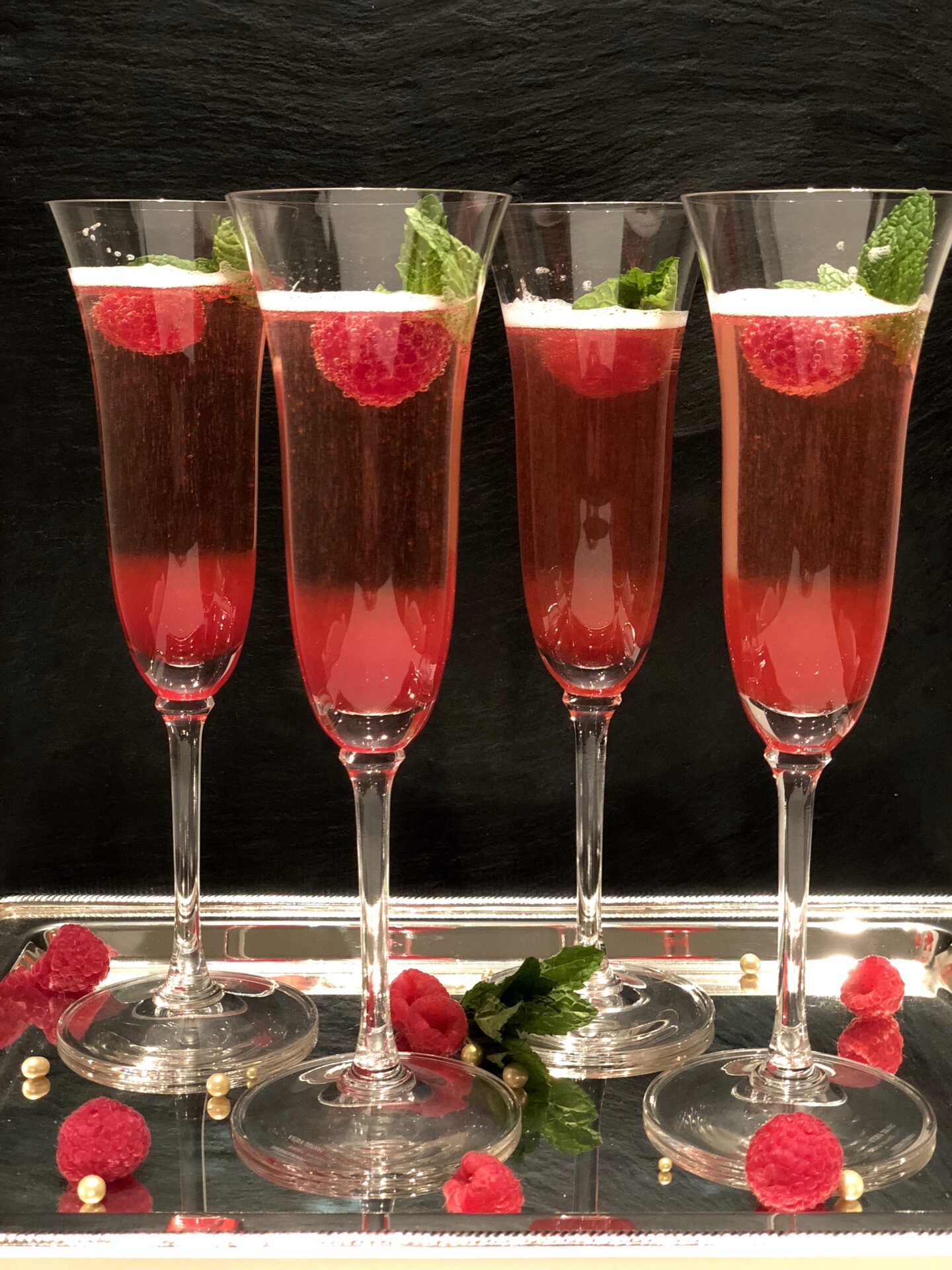 Holiday Kir Royale Cocktails with raspberries on a silver tray