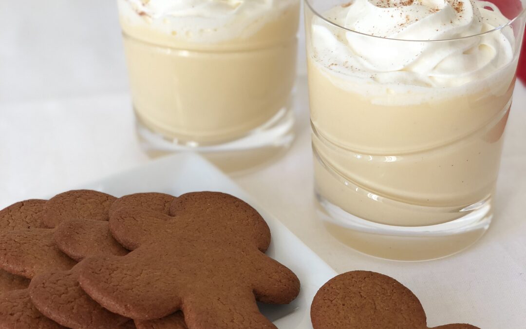 Elegant glasses of eggnog with swirls of whipped cream served with ginger bread cookies