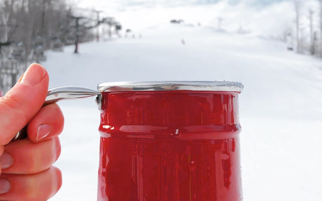 red enamel skin being raised in celebration in front of a snow covered ski hill