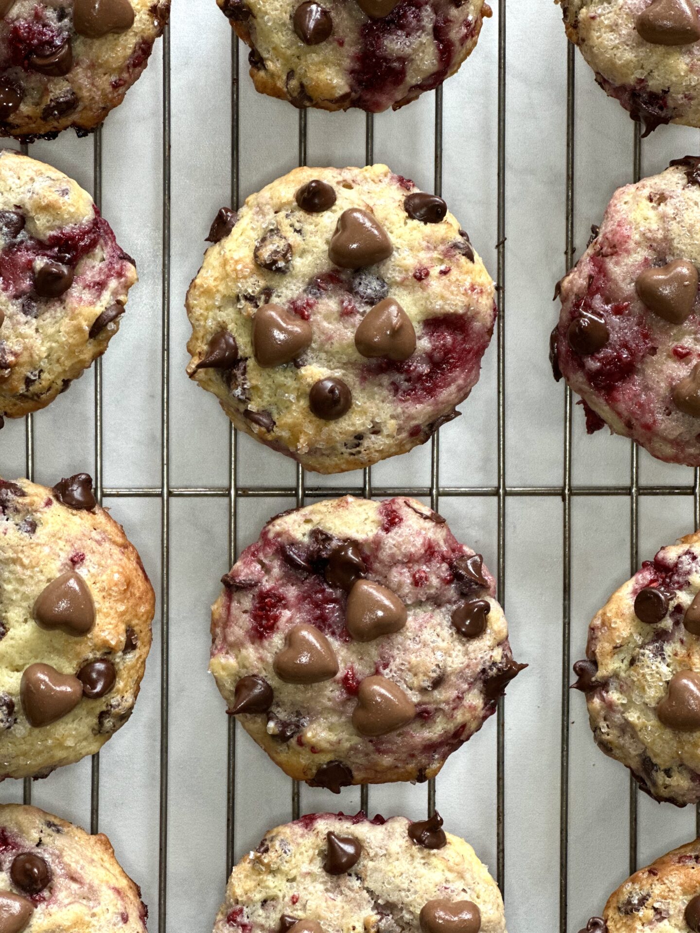 Freshly baked raspberry chocolate chip muffins, decorated for valentines day, seen from above, cooling on a rack