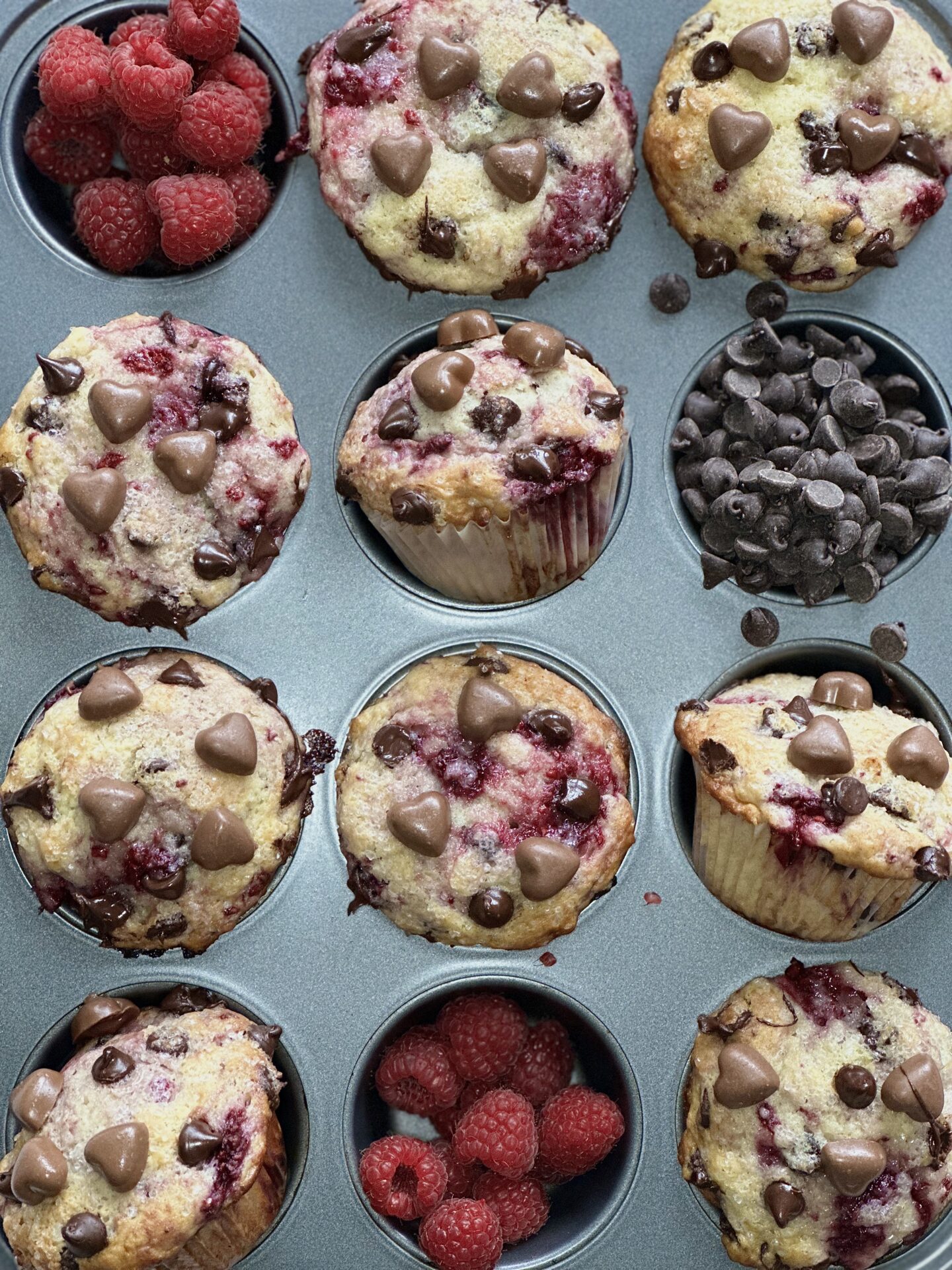  A tin of freshly baked muffins, brimming with raspberries and chocolate chips