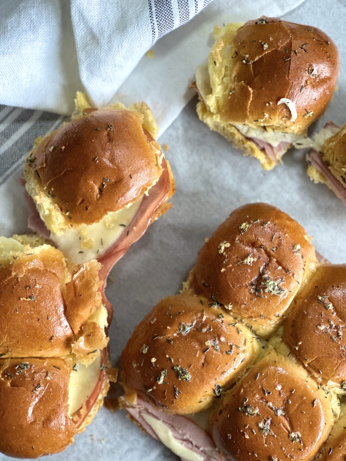 Hot and melty ham and cheese sliders topped with garlic butter, seen from above