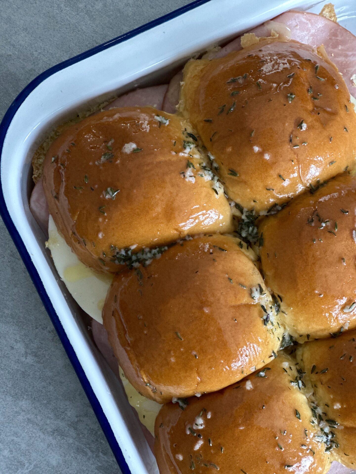 Ham and cheese sliders, brushed with garlic butter, ready for the oven.