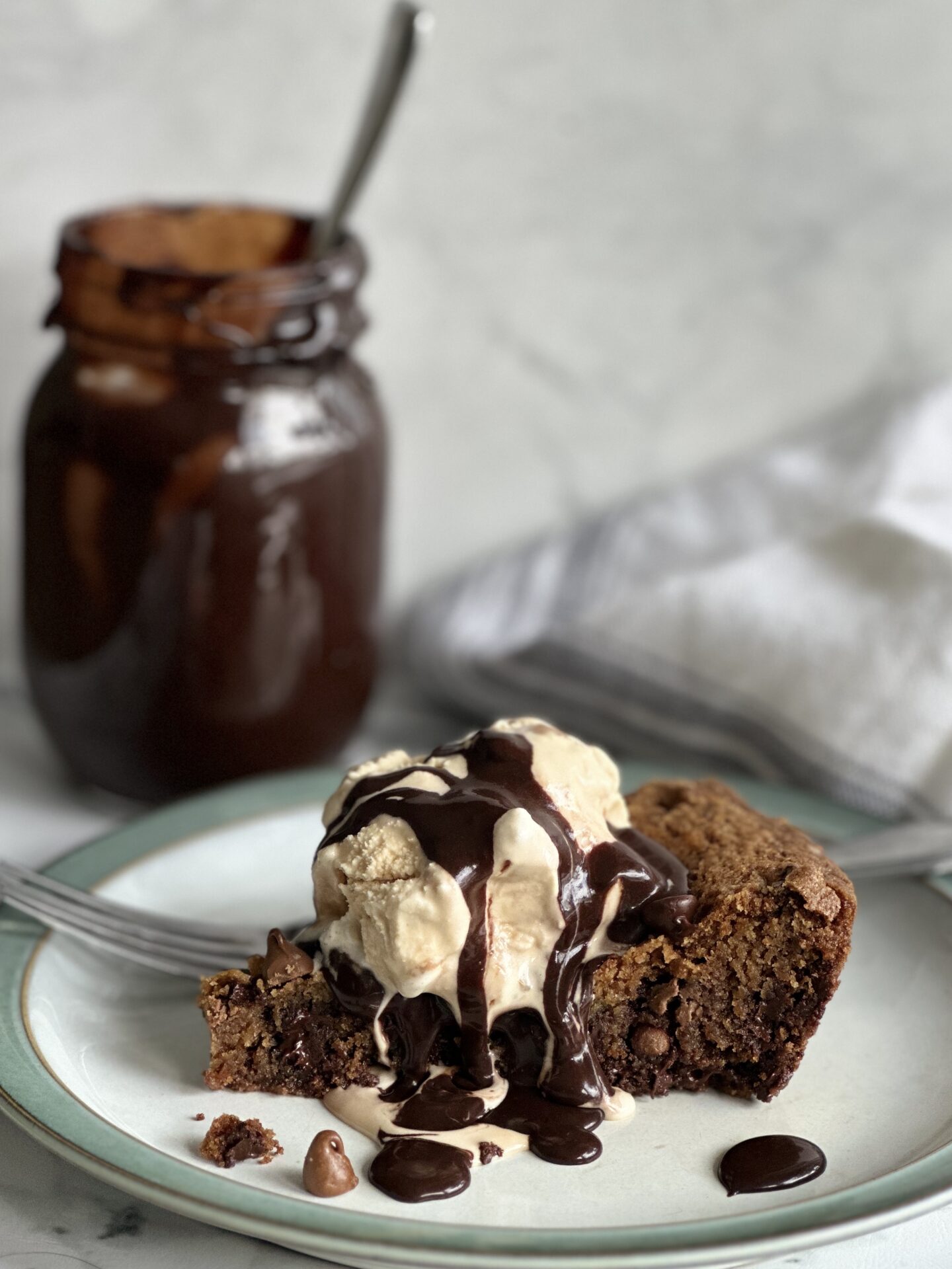 A slice of giant chocolate chip skillet cookie topped with ice cream and hot fudge sauce.