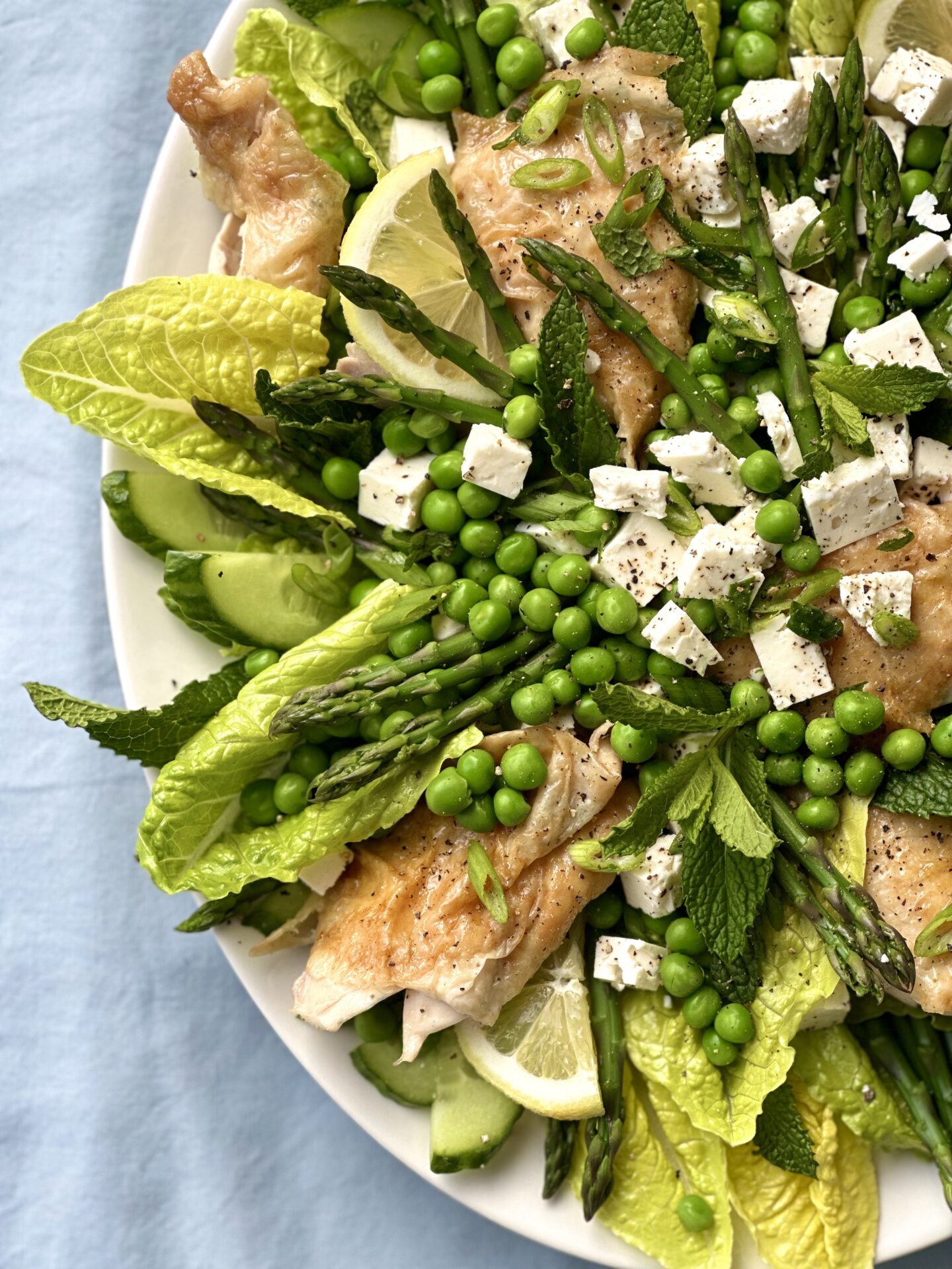 Platter of spring salad with romaine lettuce, peas, feta, roast chicken, lemon and mint