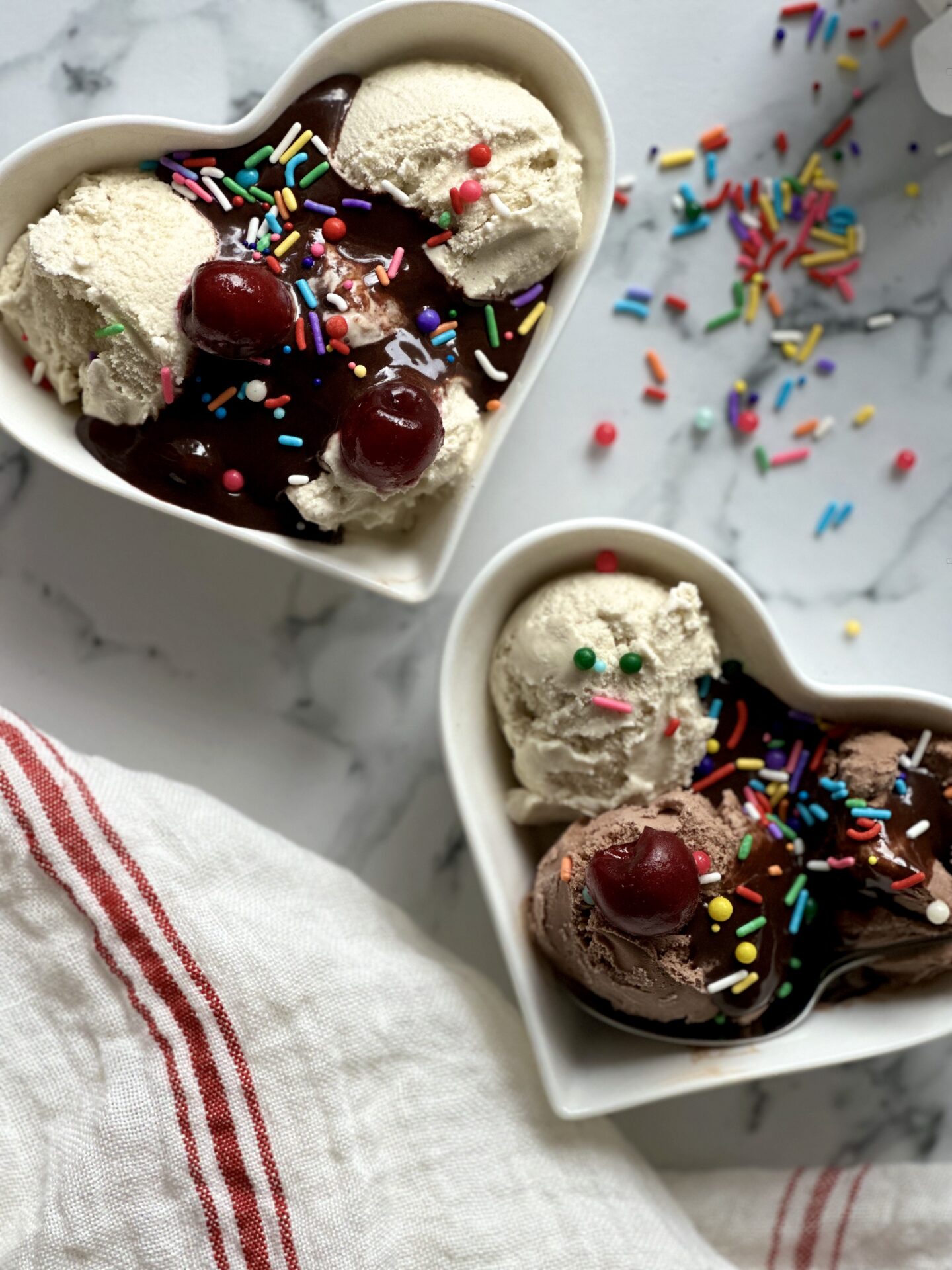 Ice cream sundaes in heart shaped bowls with hot fudge sauce and sprinkles