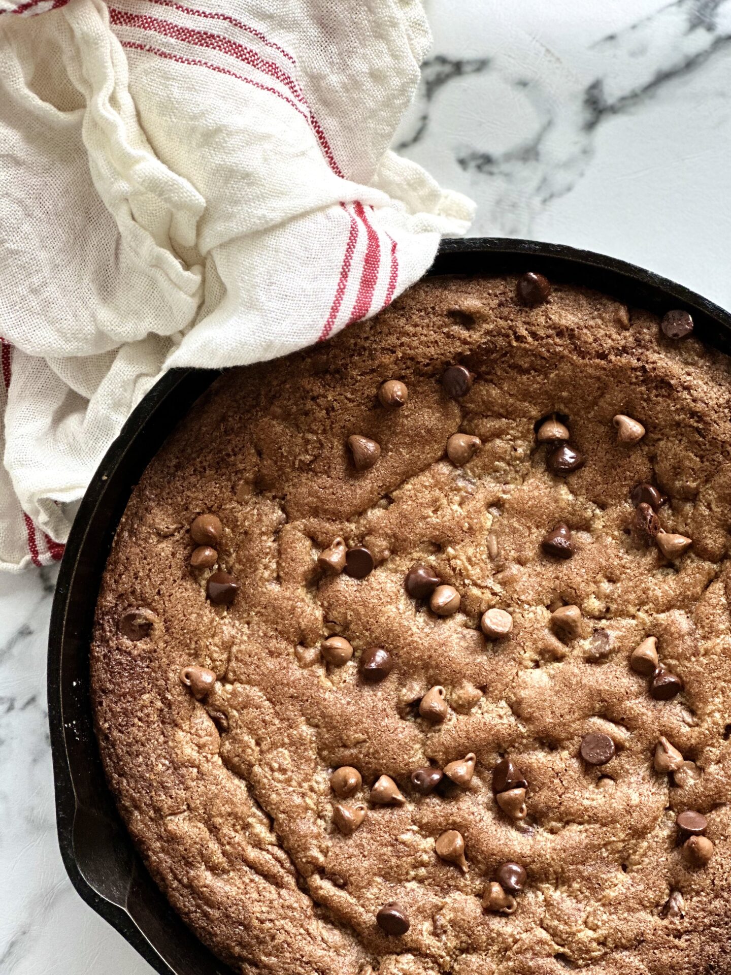 Giant deep dish chocolate chip skillet cookie warm from the oven in a cast iron pan