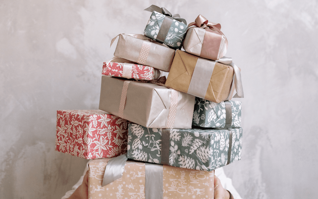 A person is hidden by a large stack of tumbling pastel coloured Christmas packages