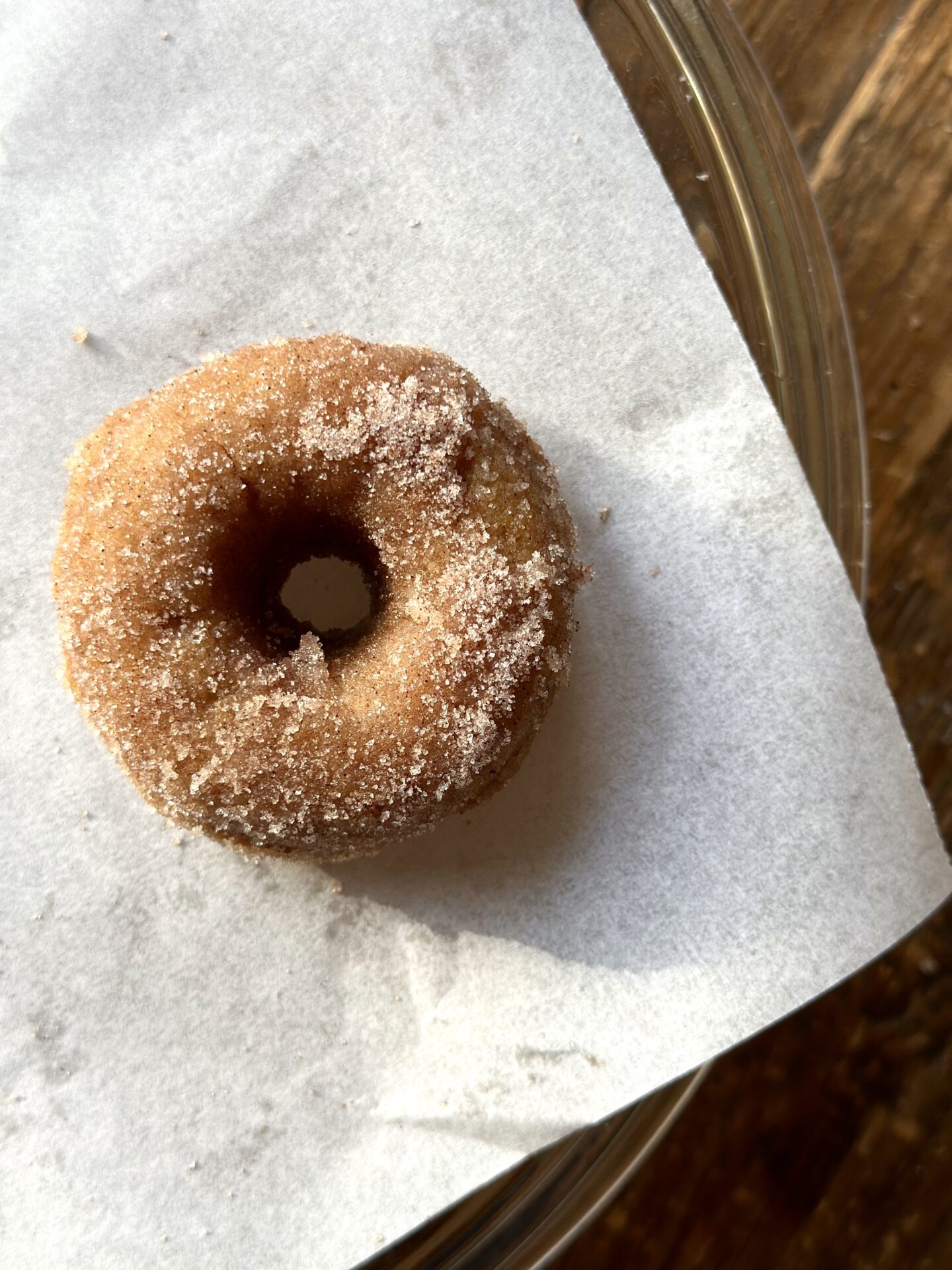 A single cinnamon sugar donut is seen from above on a piece of white parchment paper