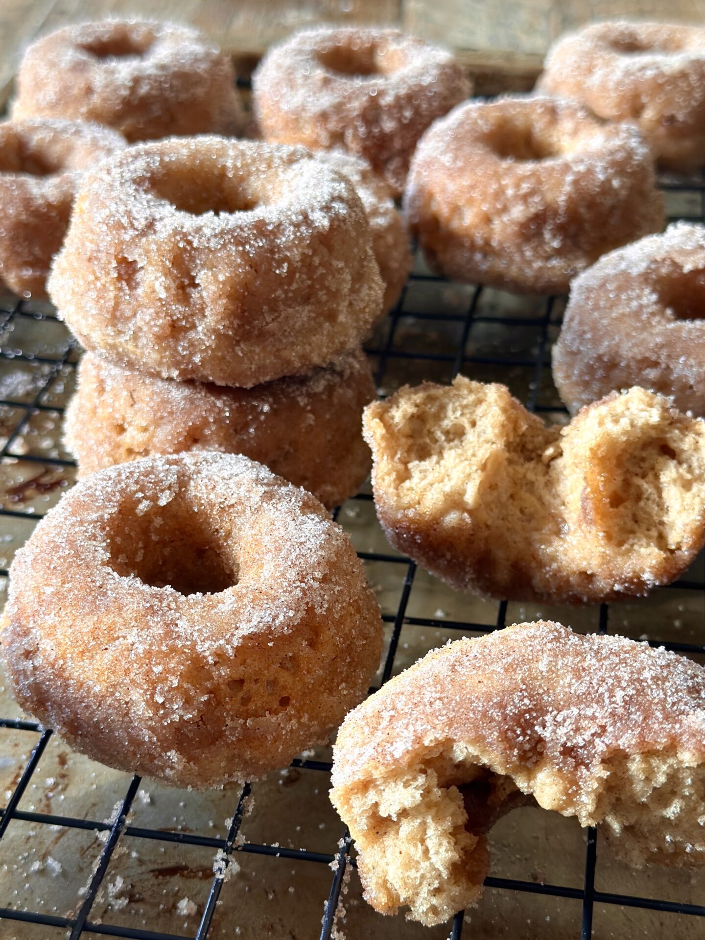 Homemade old fashioned baked cinnamon sugar donuts are stacked on a cooling rack.