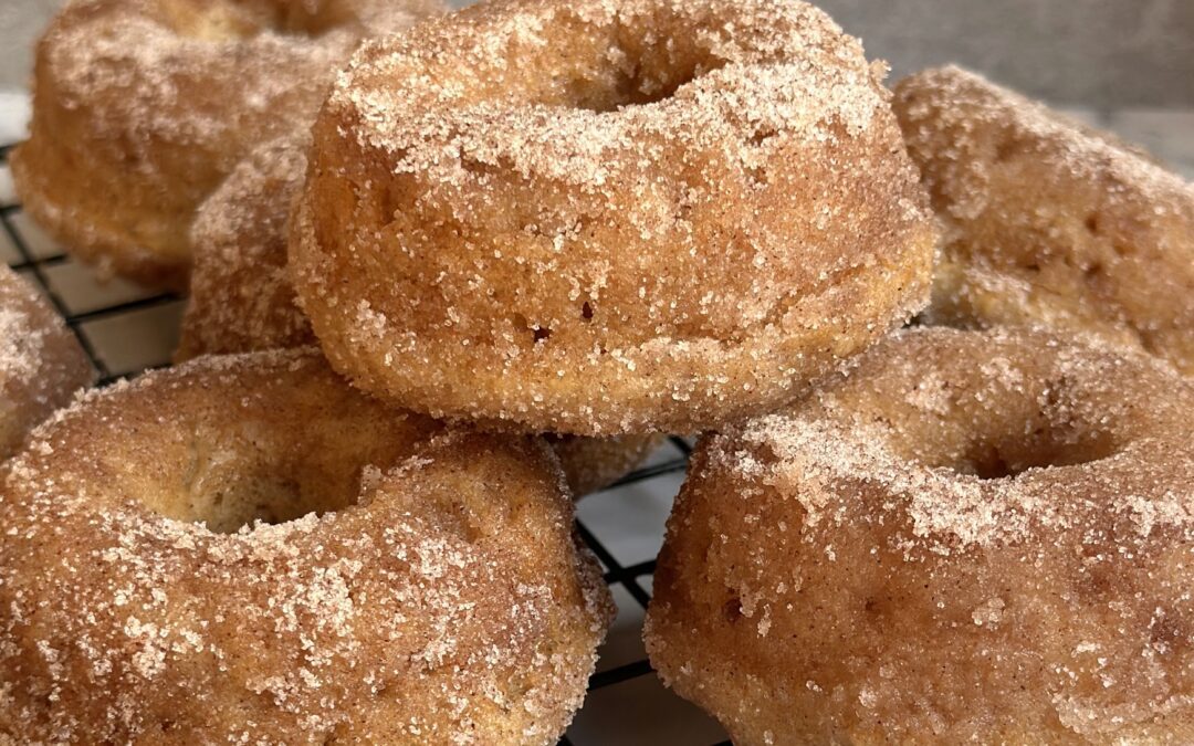 Freshly baked Cinnamon Sugar Donuts are stacked high on a cooling rack