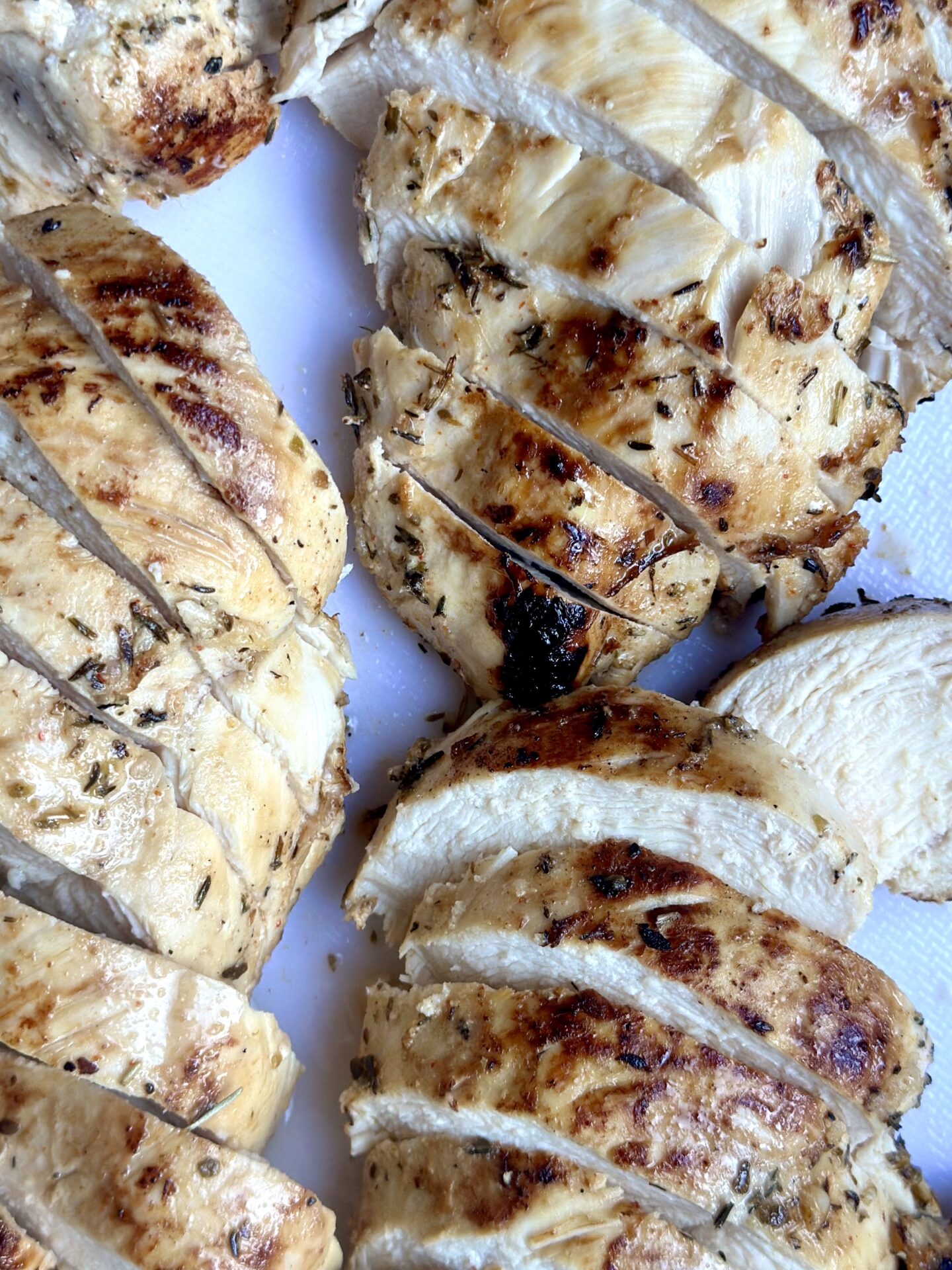 Grilled marinated chicken is sliced to show that it is perfectly cooked and juicy.