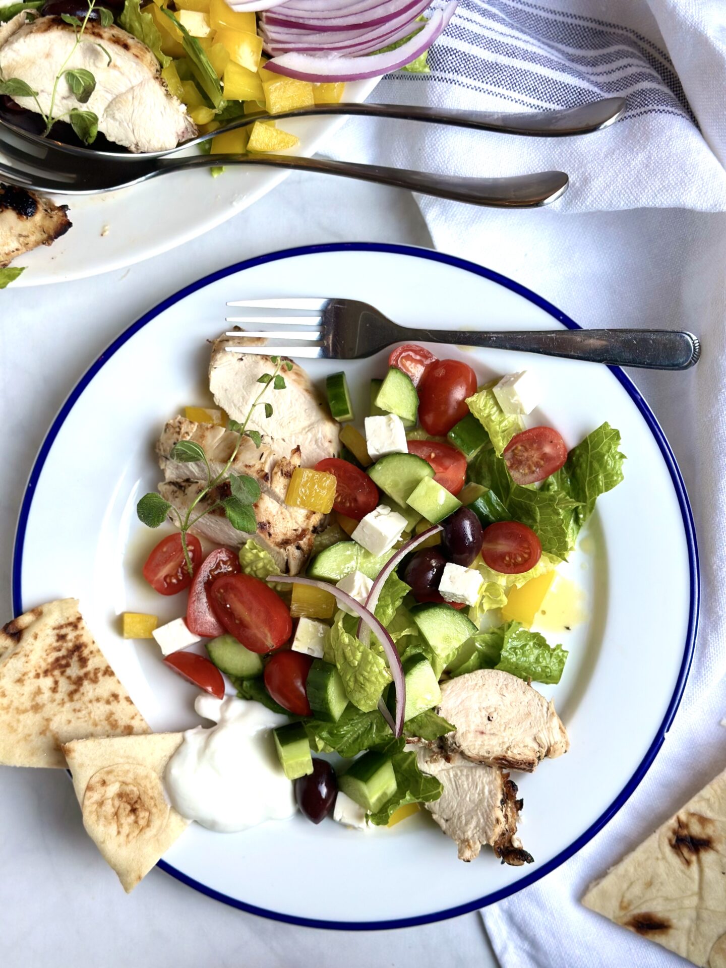A plate of Grilled Chicken Souvlaki Salad is served on a plate with pita and tzatziki