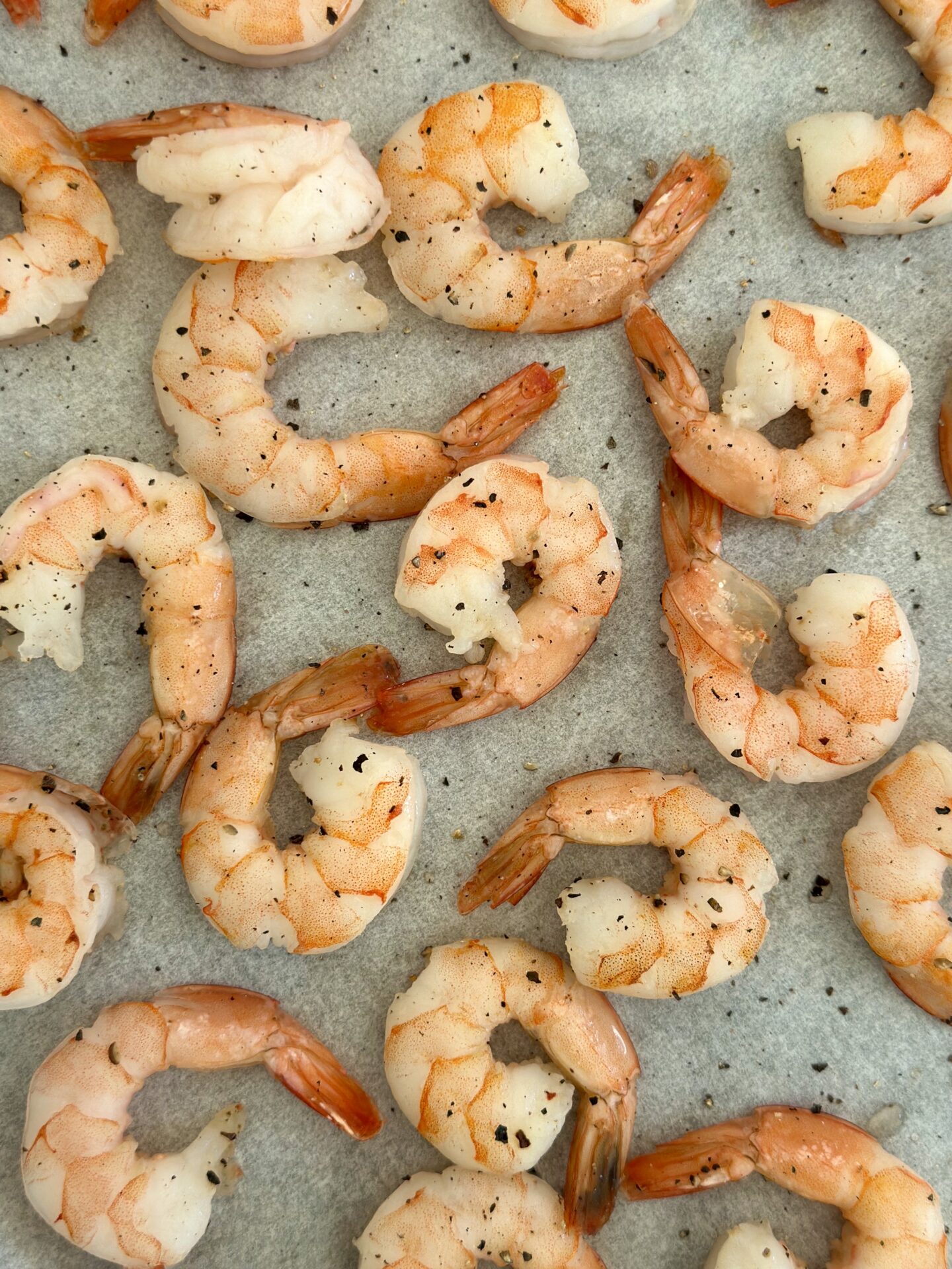 Roasted shrimp are seen from above on a baking sheet