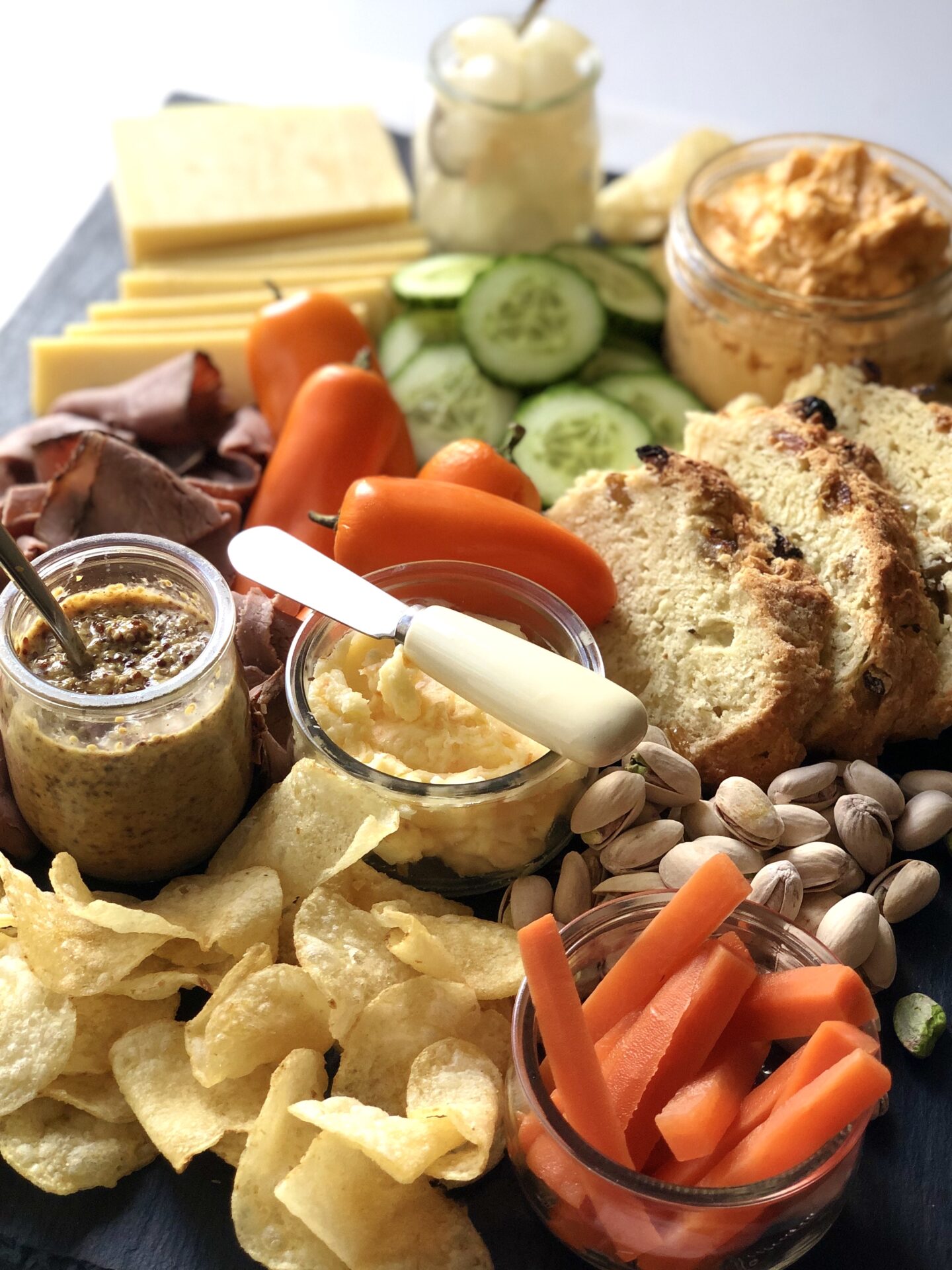 A St Patrick's Day charcuterie board featuring Irish cheddar, roast beef, beer cheese, pickled carrots and Irish soda bread is seen from above.