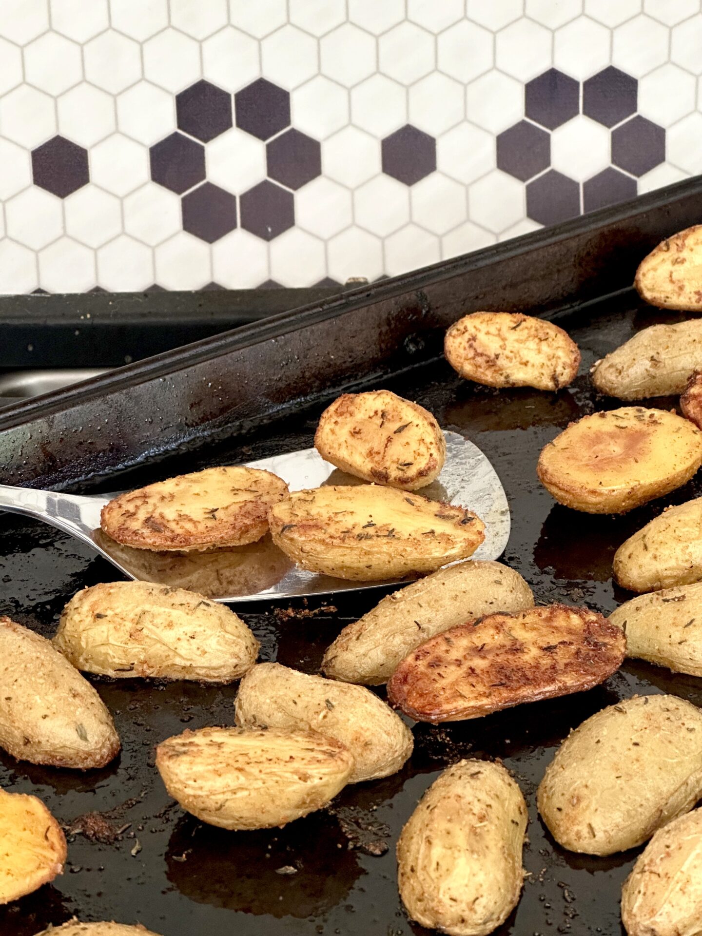 A baking sheet of fresh and hot roasted fingerling potatoes rests on a cook top ready to be   served