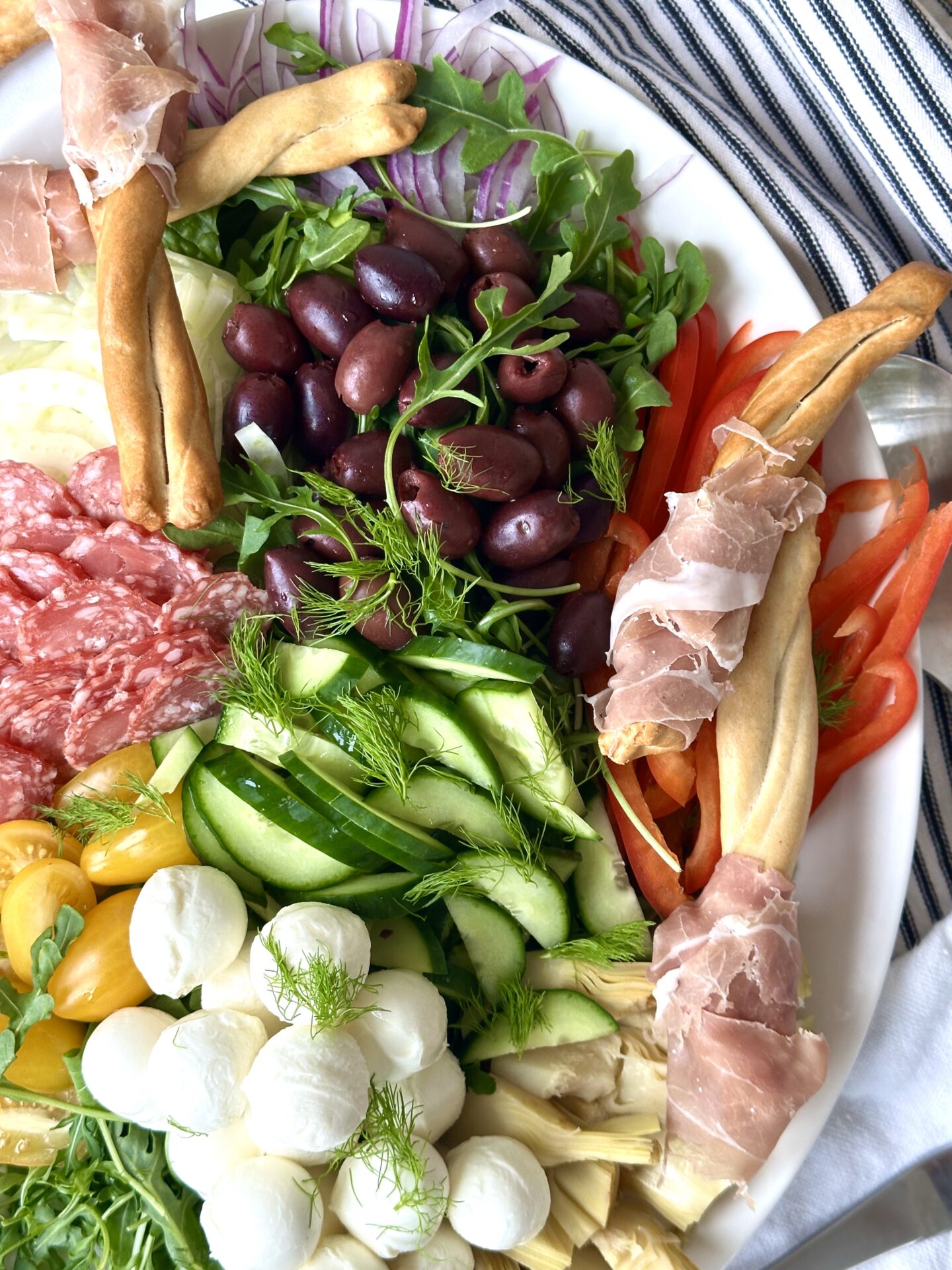 A serving platter full of Antipasti Salad with Prosciutto Wrapped Breadsticks is seen from above