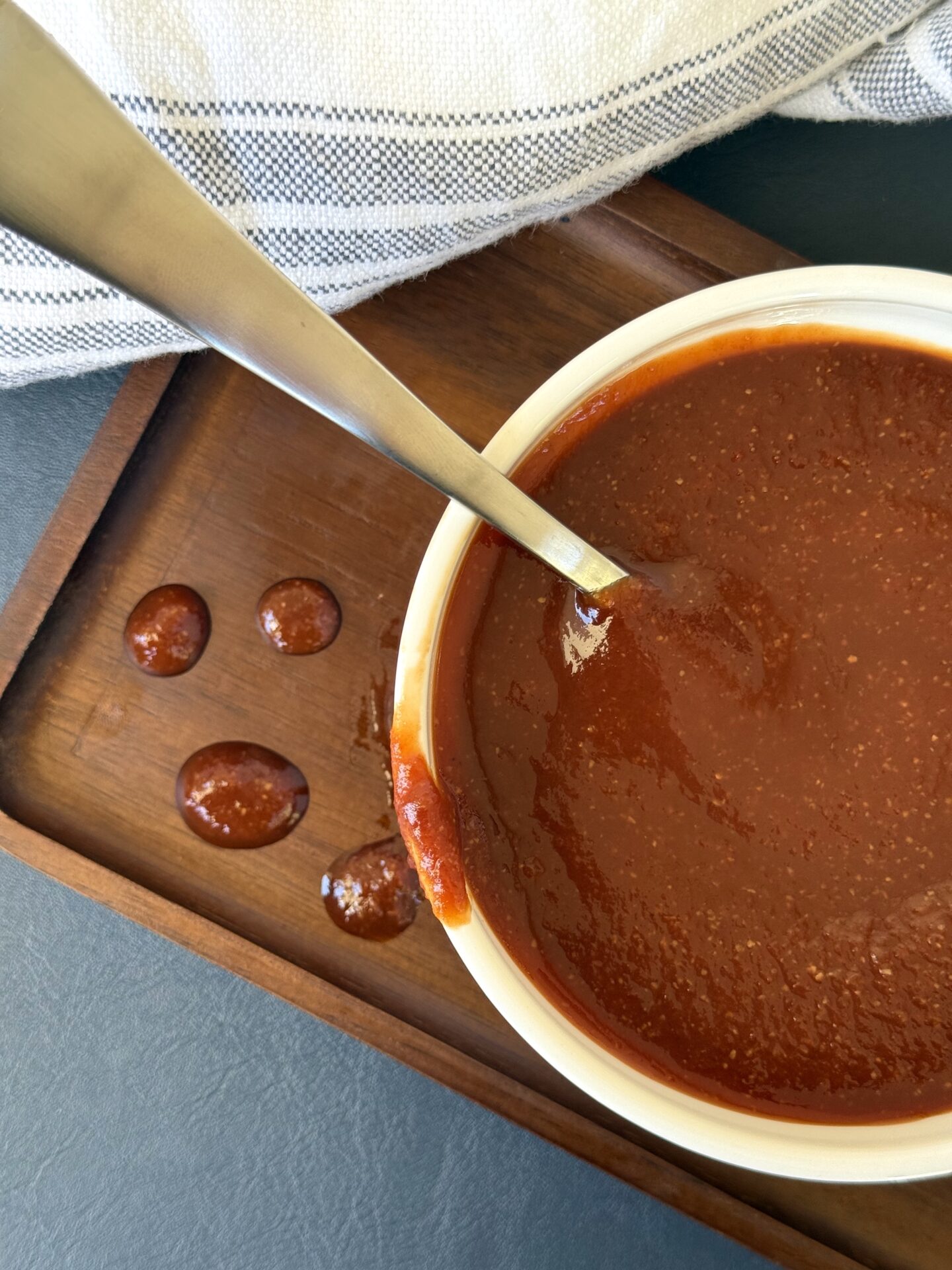 A bowl of homemade Guinness barbecue sauce is seen from above, dripping onto a wooden board.